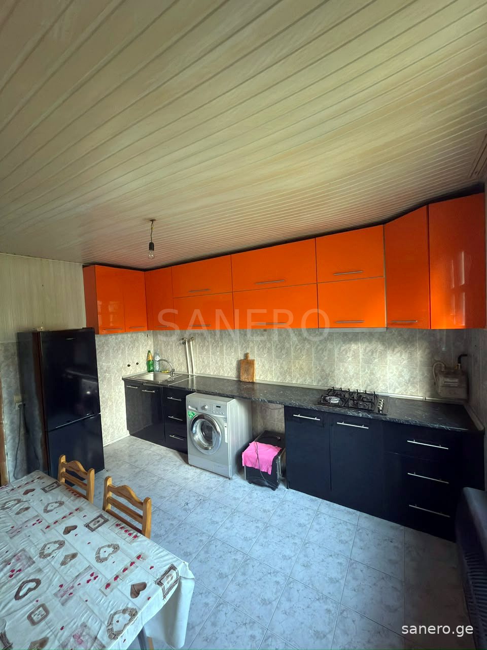 Separate kitchen with gas cooktop, refrigerator and washing machine
