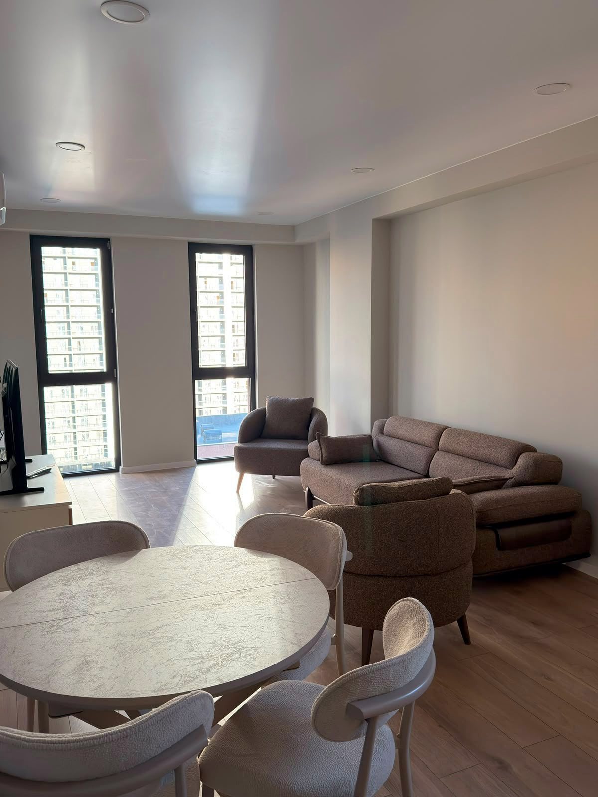 Living room with tall windows, sofa and dining table