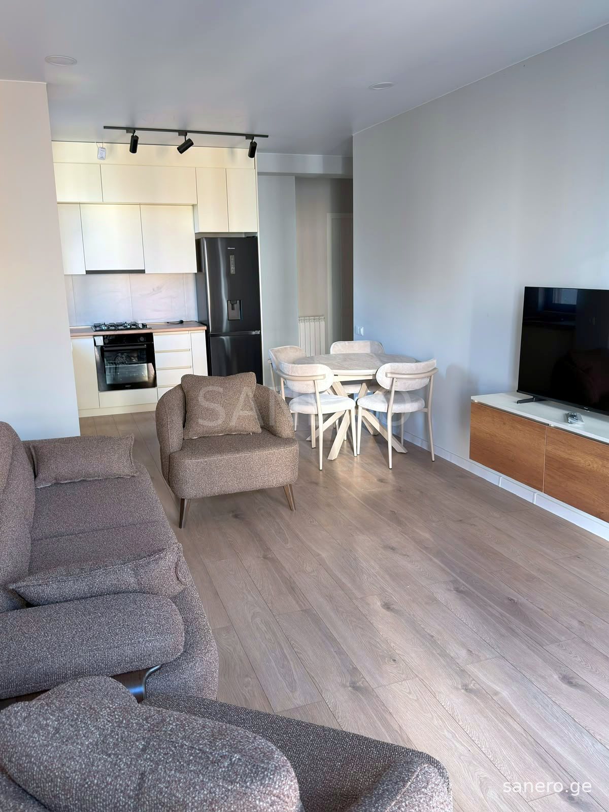 Living room with TV area, dining table and kitchen